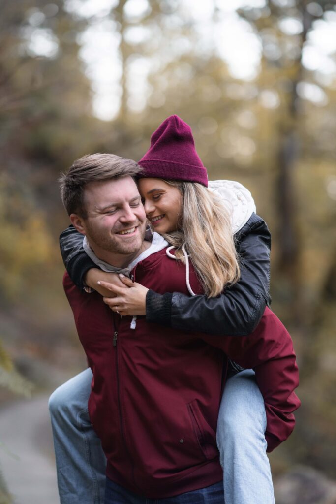 Engaged couple cuddling on hiking trail