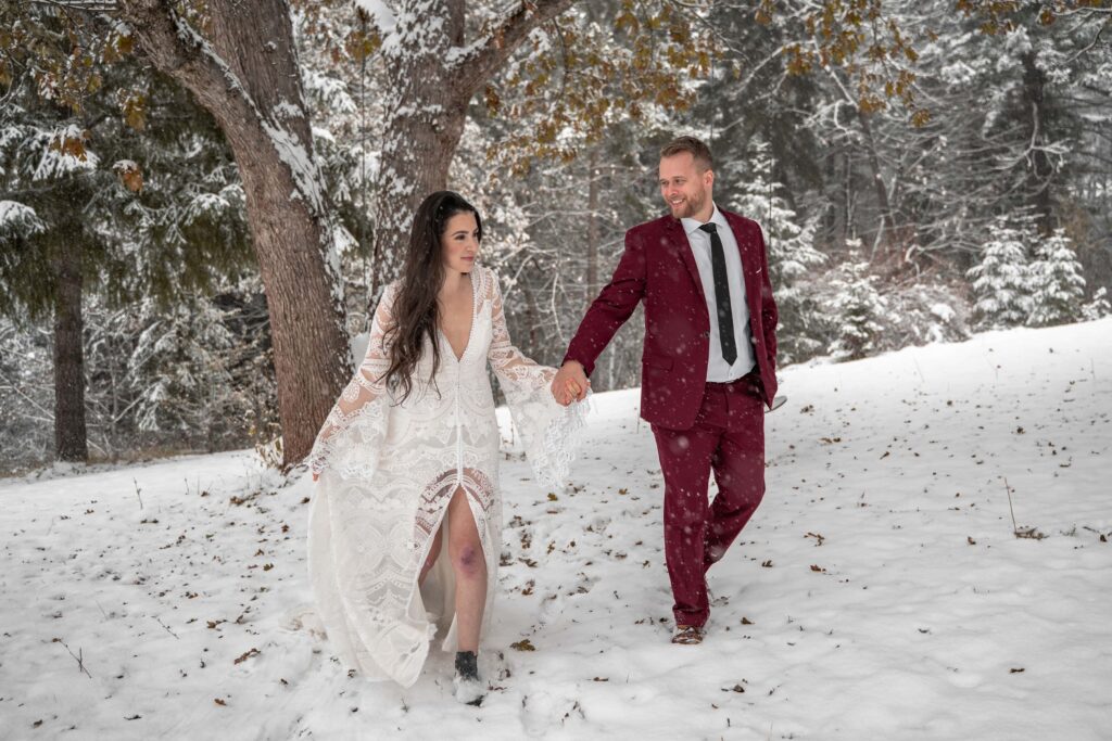 couple hikes through snow in winter forest adventure session