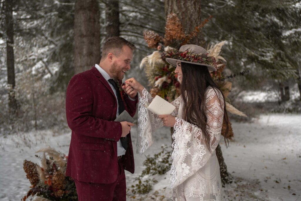 couple reads vows in elopement ceremony in the forest red and white