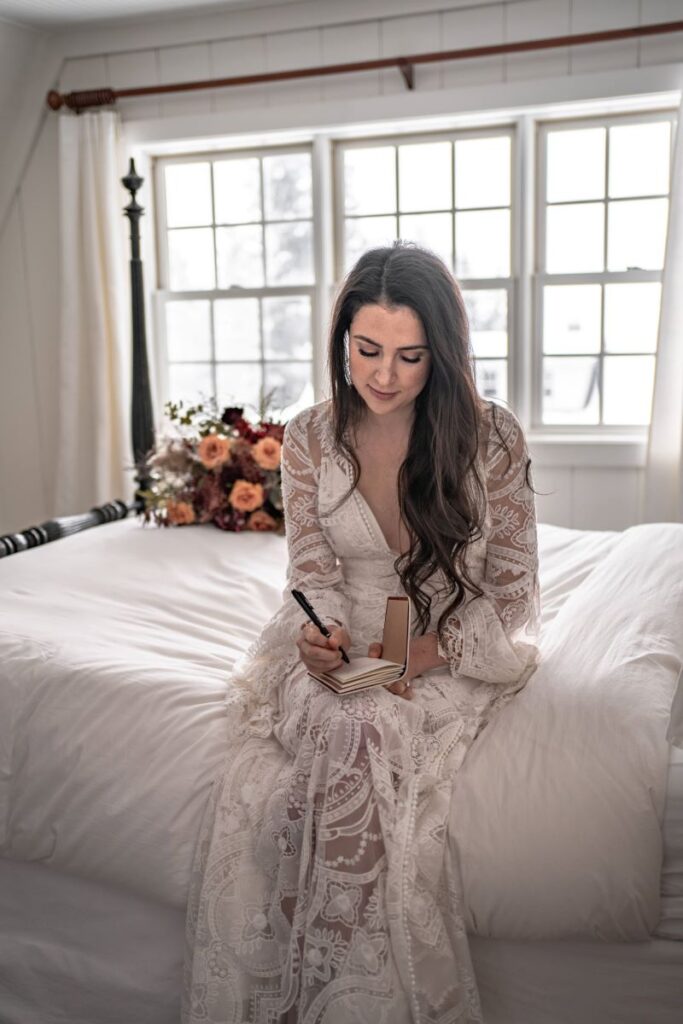 bride writing vows getting ready in white dress for winter elopement in an airbnb in Oregon