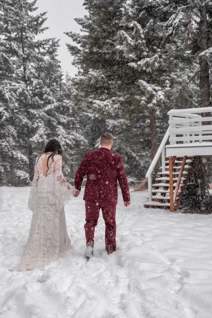 bride and groom walk back to cabin in snowy elopement