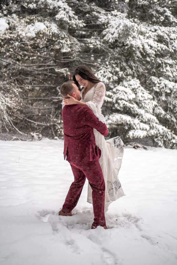 groom picks up bride in snowy forest